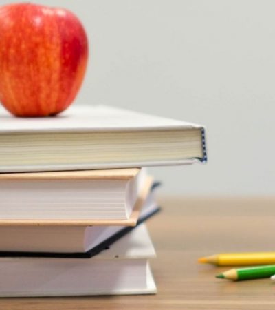 placeholder Apple on top of a stack of books on a desk
