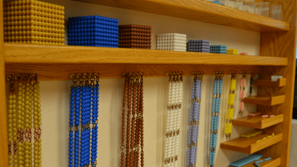 Shows the beads used to teach math skills organized in a wooden shelf